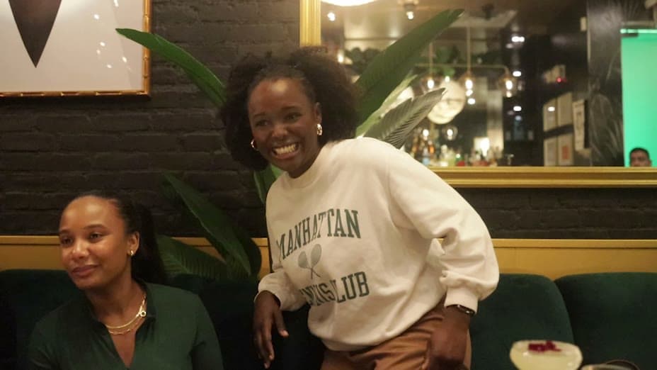 Two guests laughing together on a green velvet banquette